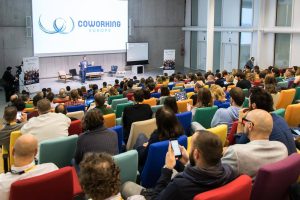 Numerous people seated in a conference hall at the Coworking Europe conference in 2018.