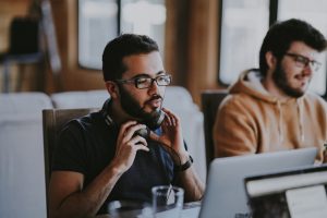 A man taking off his headphones at his workspace.